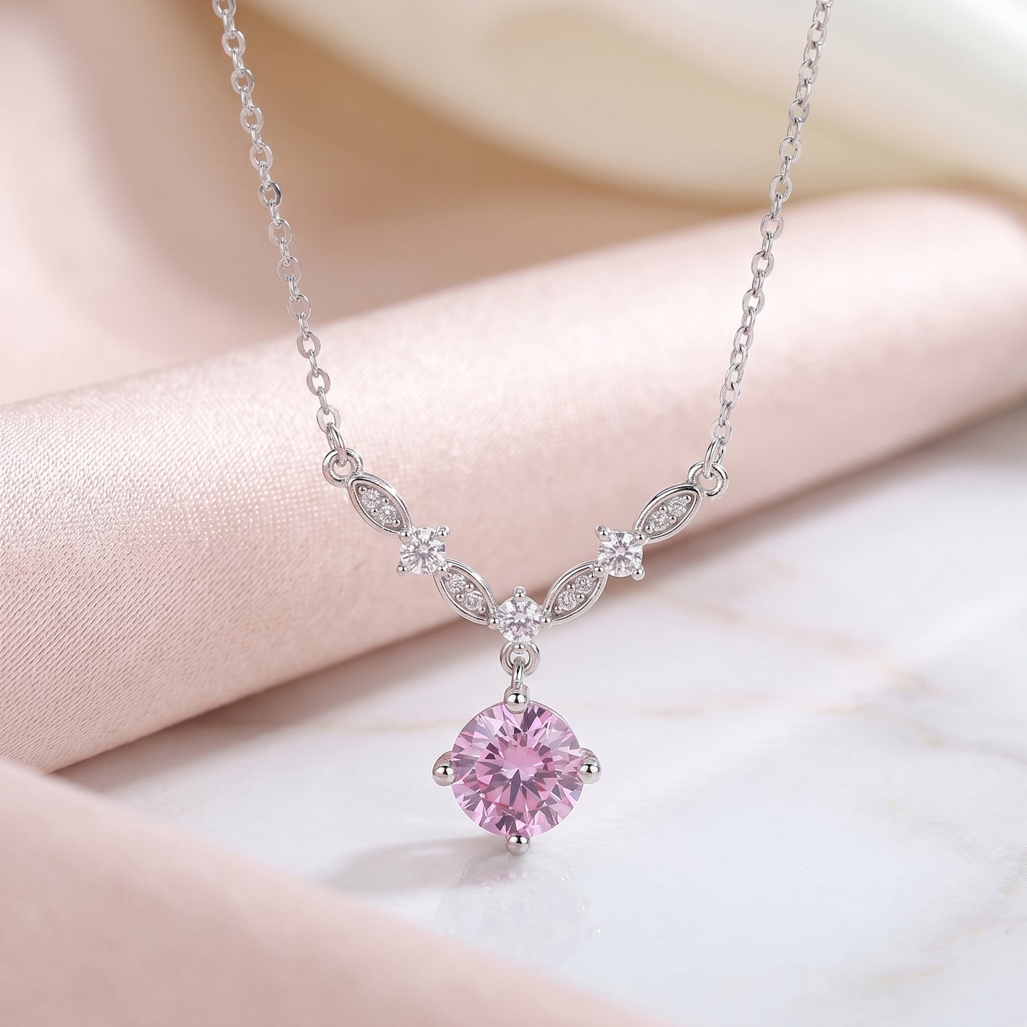 Pink cubic zirconia floral vine necklace on soft pink satin background