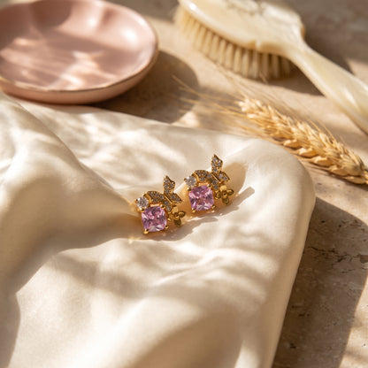 Pink Gold Butterfly Garden stud earrings displayed on soft champagne satin