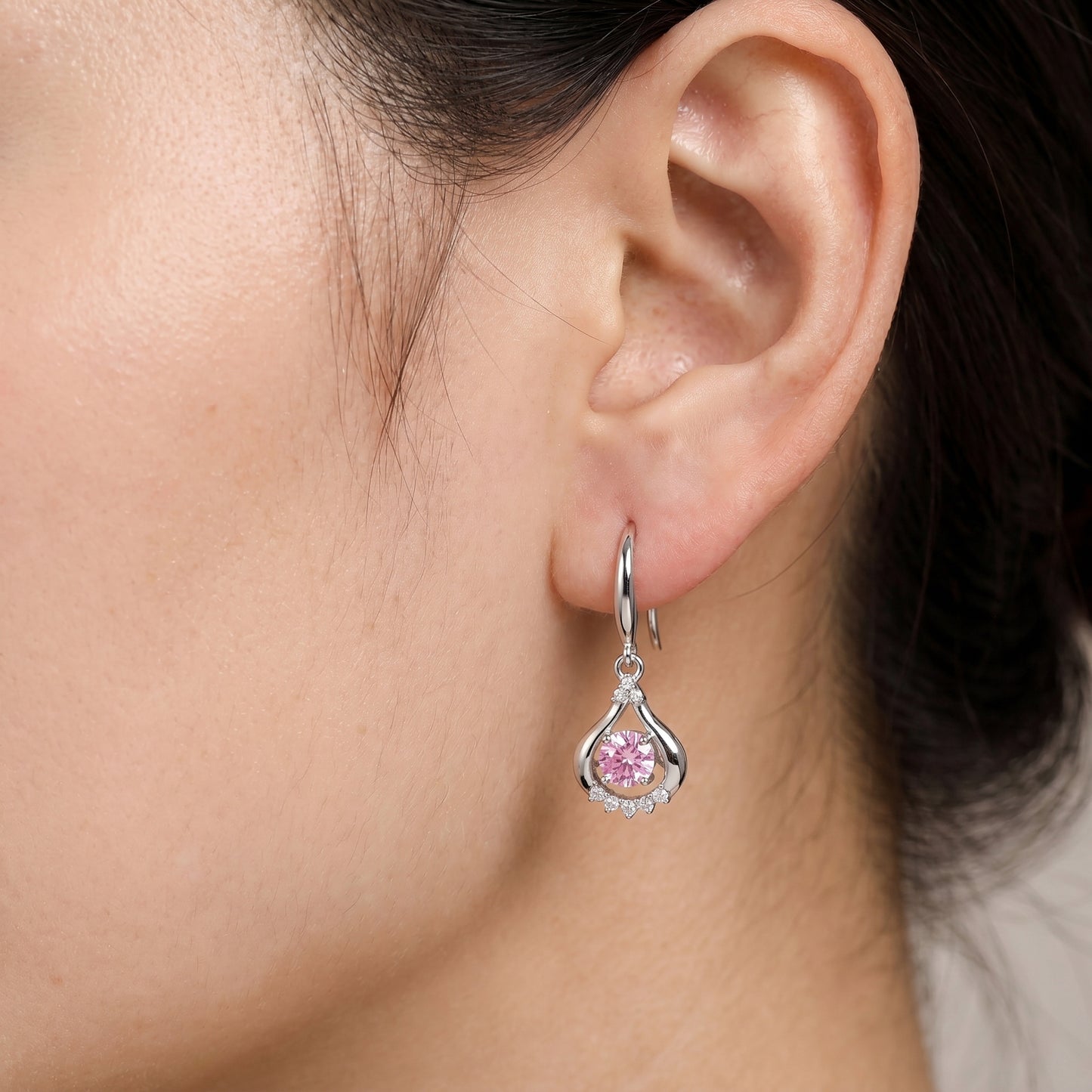 Pink teardrop dancing cubic zirconia earrings worn on ear in 925 sterling silver