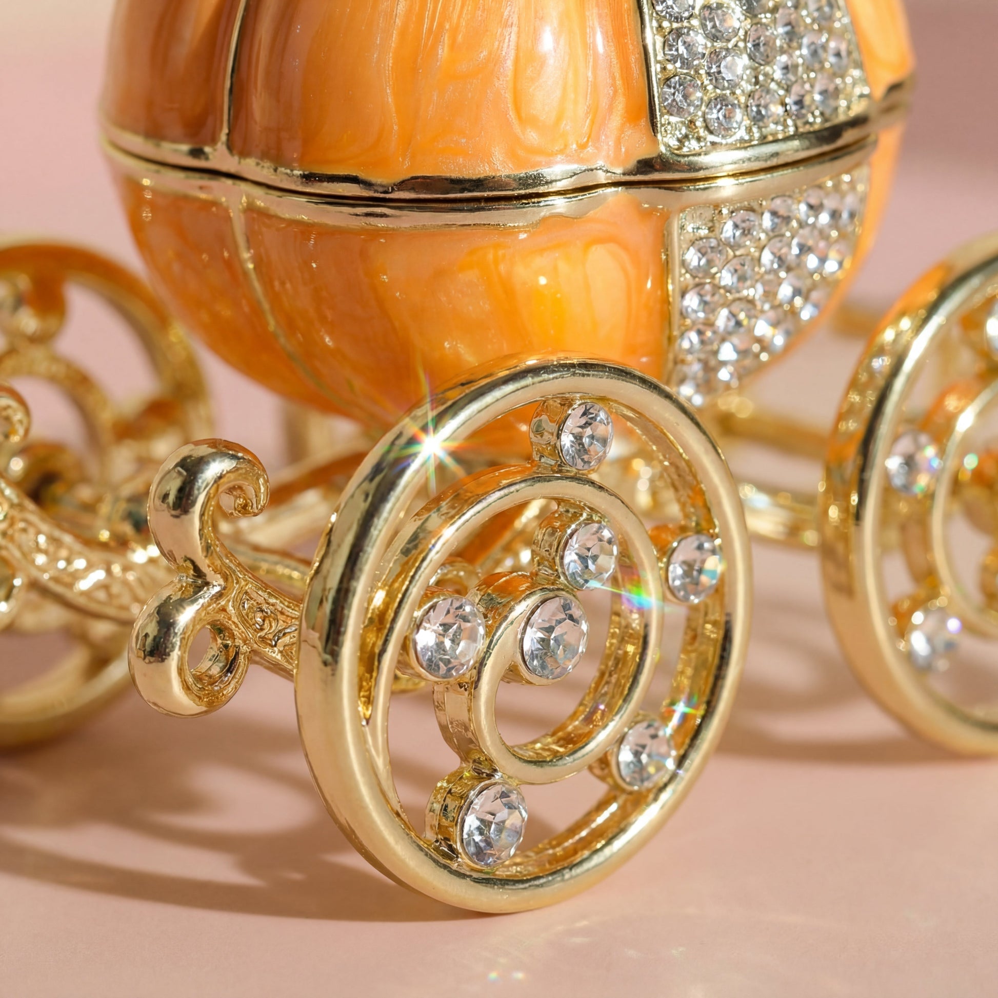 Gold wheel detail of a vintage orange pumpkin carriage jewellery box with sparkling accents and decorative carriage design.