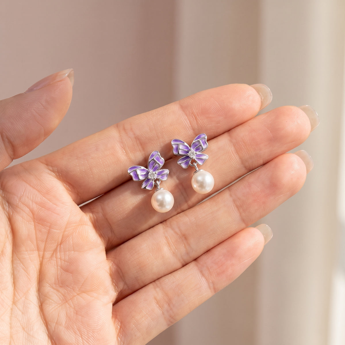 Purple butterfly 925 sterling silver pearl drop earrings held in hand for scale