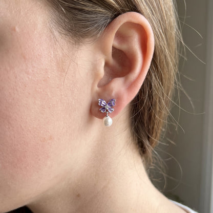 Side view of purple butterfly pearl drop earrings worn on the ear