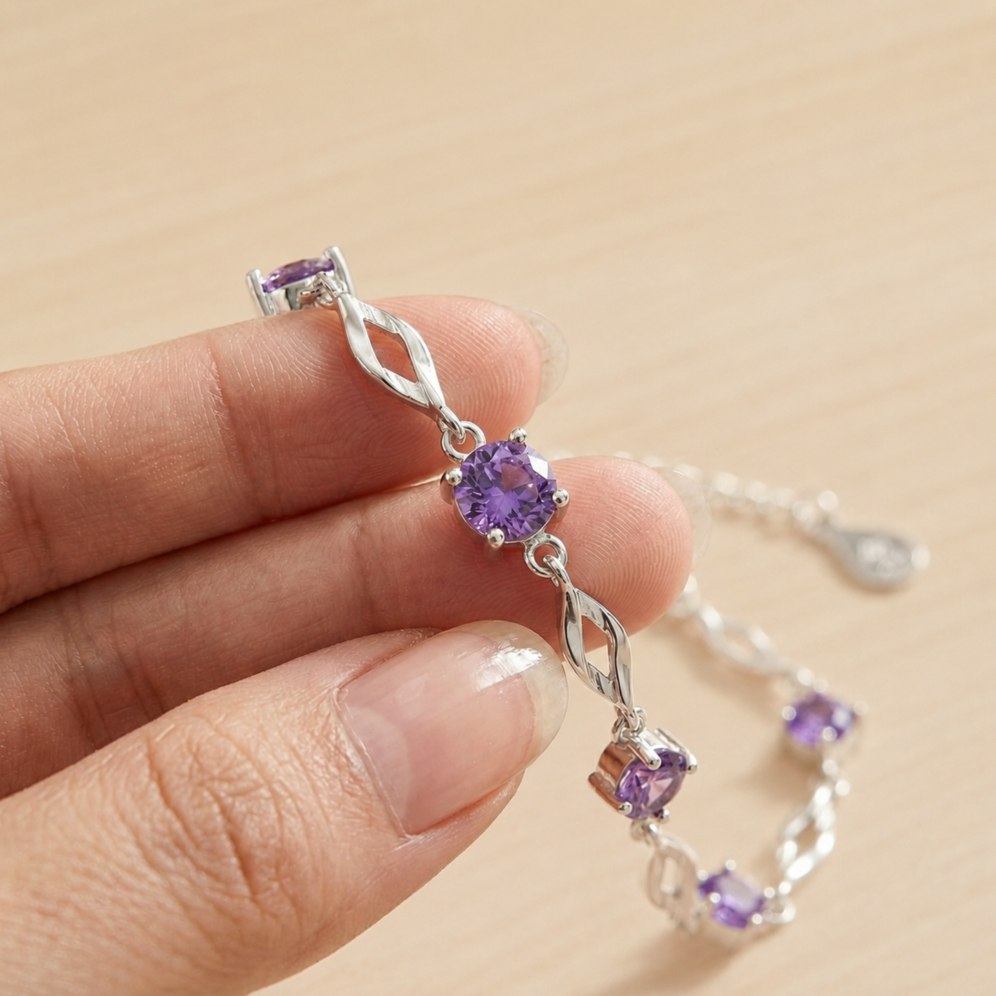 Hand holding the purple cubic zirconia 999 fine silver bracelet to show the stone and link details