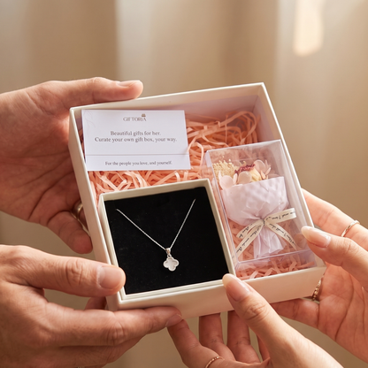 Hands presenting a romantic clover necklace and dried red rose gift set for her