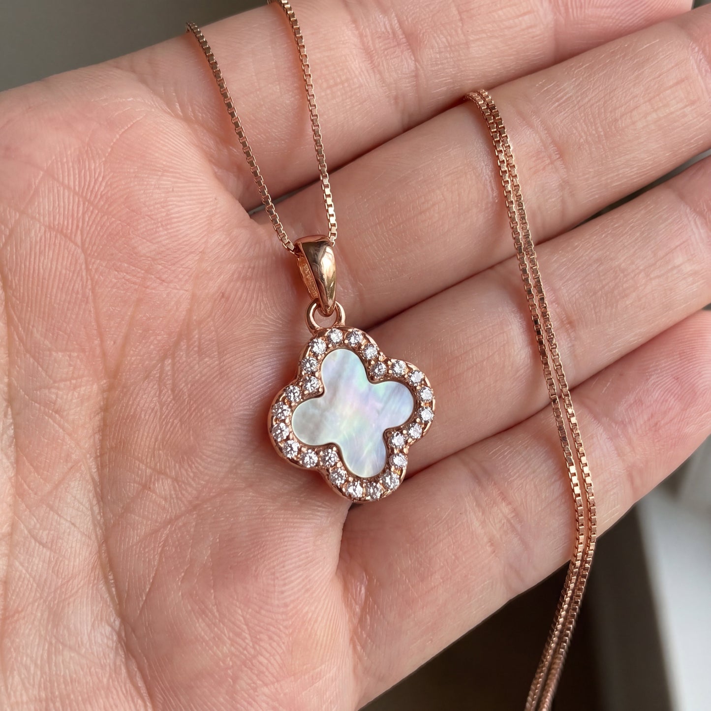 rose gold white four leaf clover necklace held in hand for size reference
