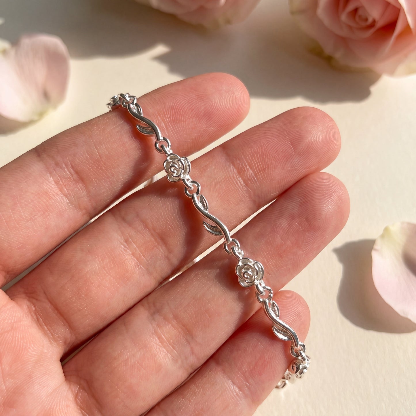 Handheld view of the Rose of Love bracelet showing the delicate rose design and silver-tone finish.