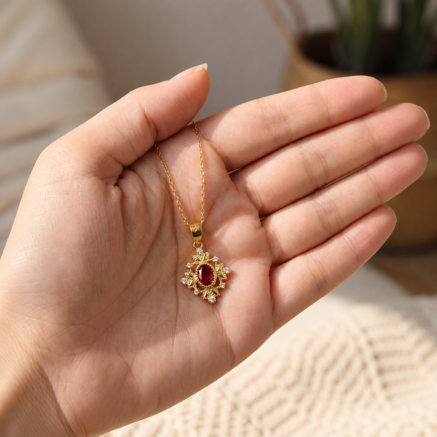 Gold ruby red vintage pendant necklace displayed in hand to show its size and fine details