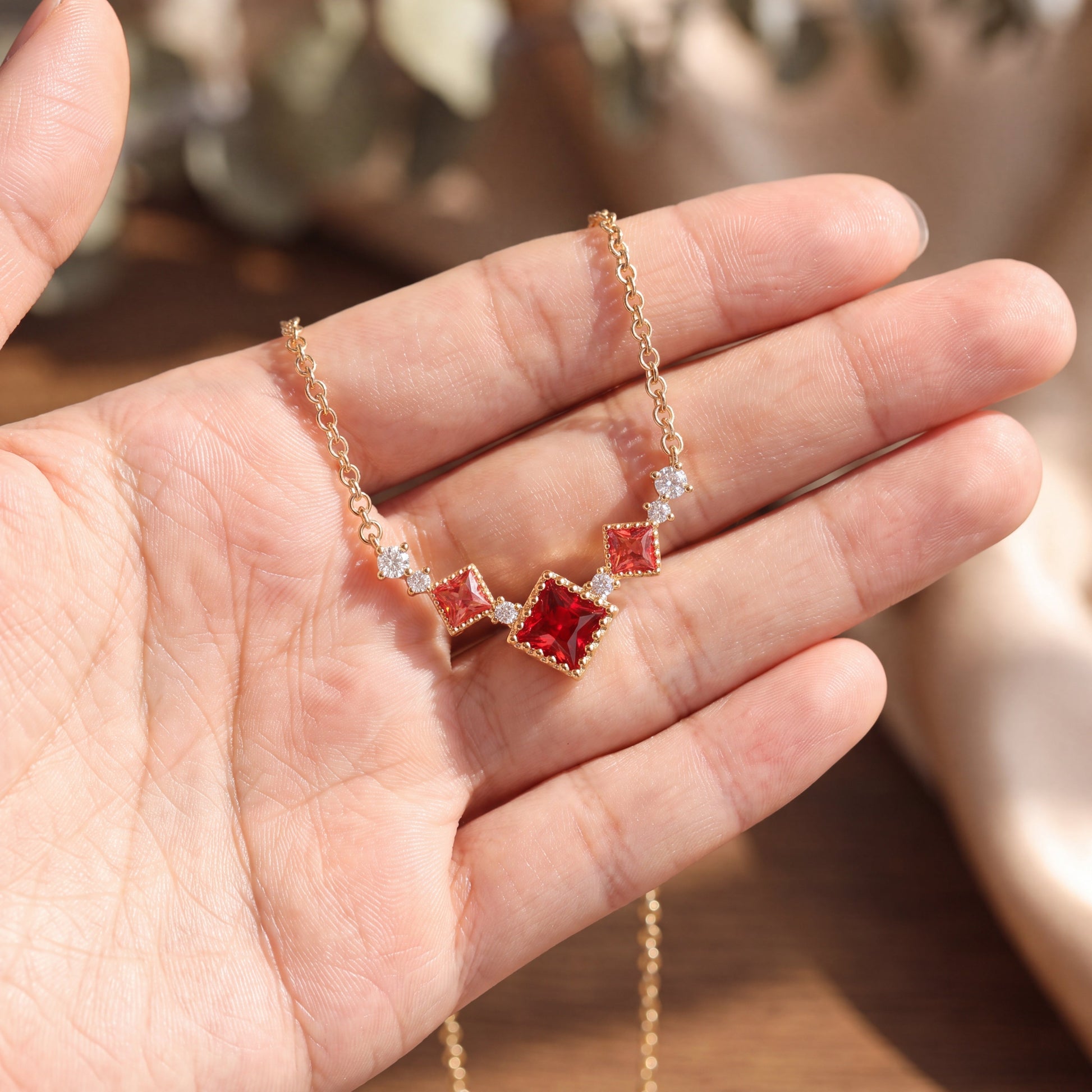 Gold Scarlet Vintage red cubic zirconia necklace displayed by hand in natural light