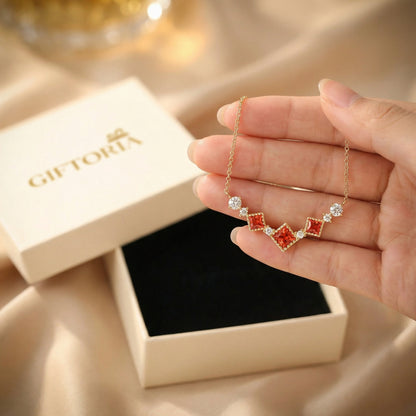 Hand holding scarlet vintage red cubic zirconia necklace with Giftoria gift box