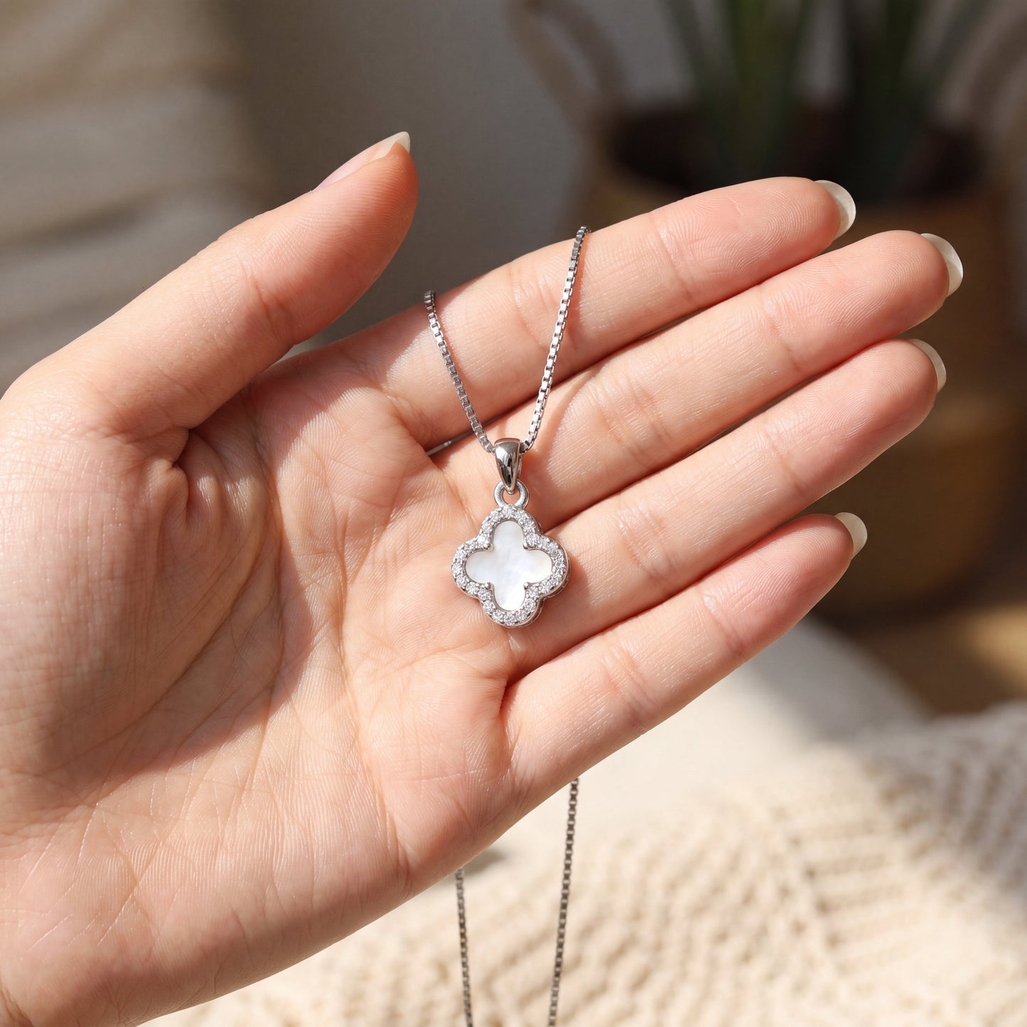 rose gold white four leaf clover necklace held in hand for size reference