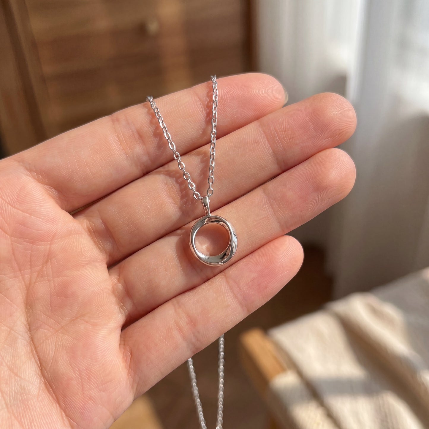 Small sterling silver open circle pendant necklace shown in hand for size reference
