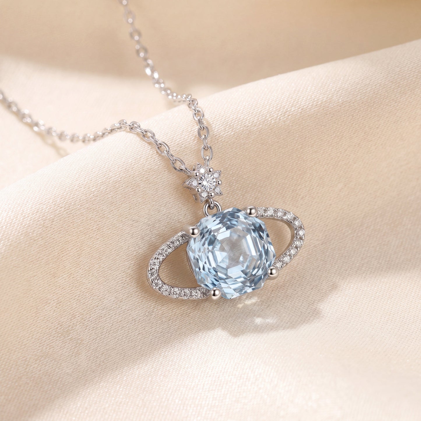 Sparkling blue planet star necklace on satin fabric with soft celestial jewellery style