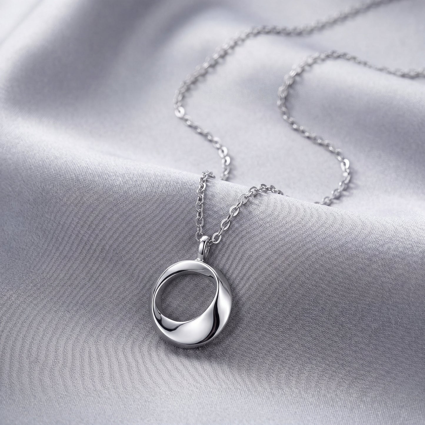 Sterling silver open circle pendant necklace styled with white flowers on soft linen