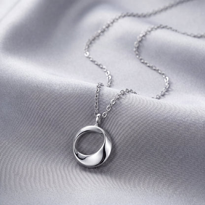 Sterling silver open circle pendant necklace styled with white flowers on soft linen