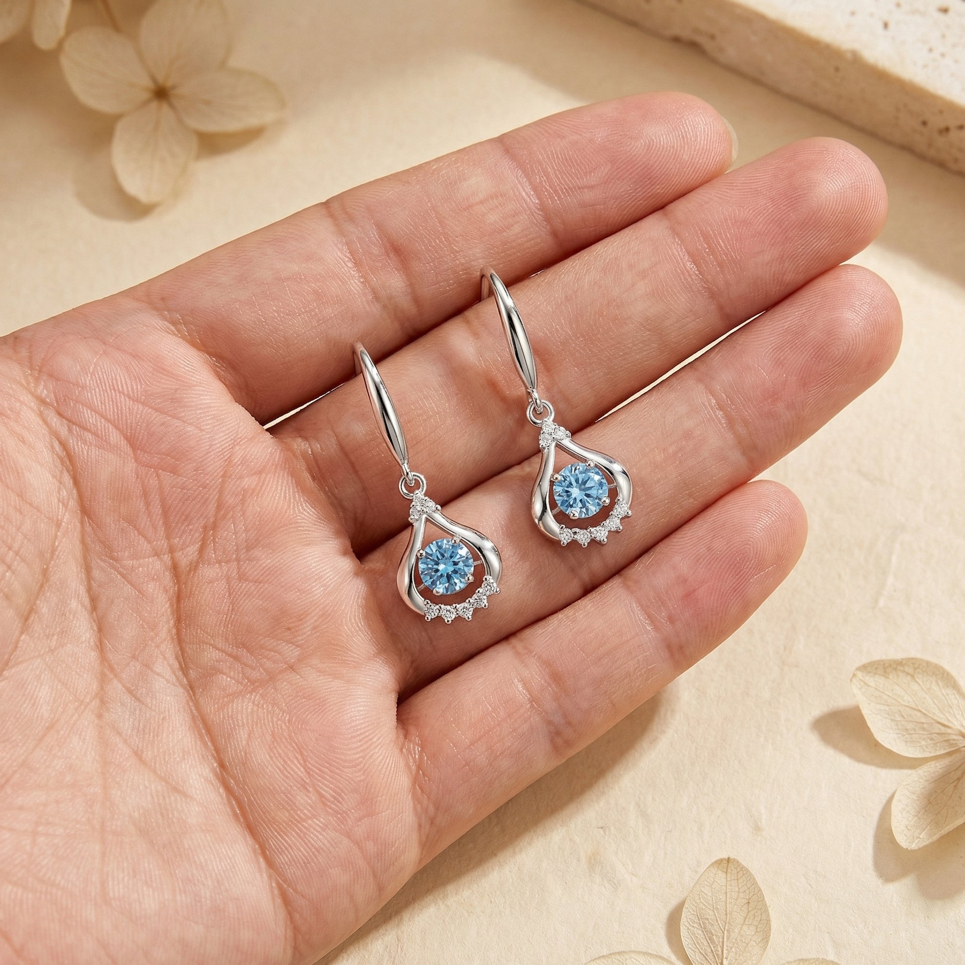 Blue colour teardrop dancing cubic zirconia earrings shown in hand for size reference