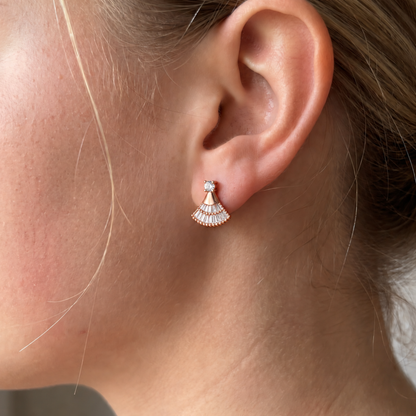 Rose gold fan-shaped moissanite stud earring worn on an ear.