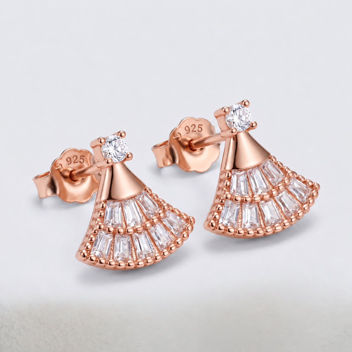 Angled view of the rose gold fan-shaped earrings, showing the studs and stone-set design.