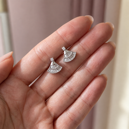 Pair of silver fan-shaped moissanite earrings resting on a hand.
