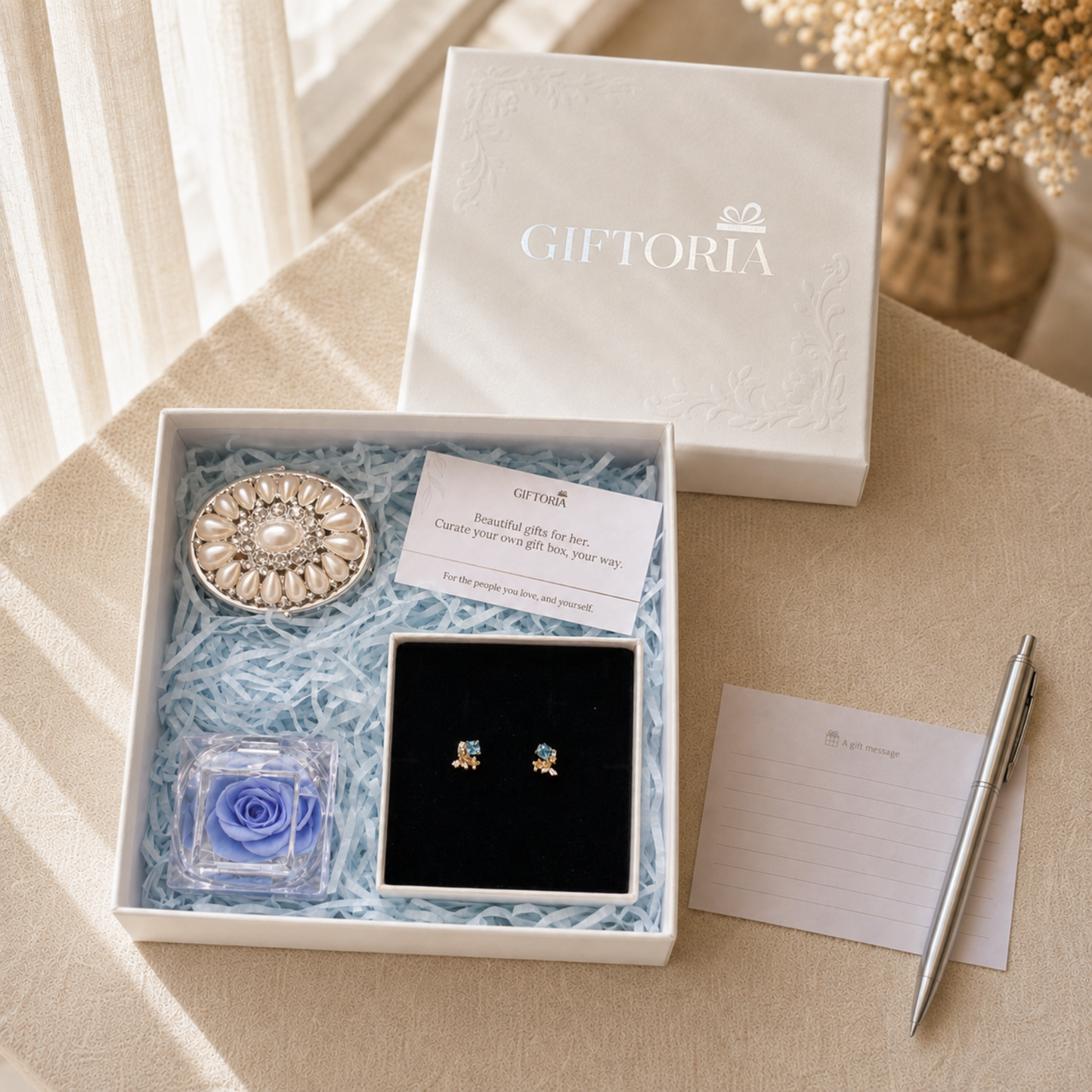 Open Giftoria gift set beside its lid and gift card with butterfly earrings, blue rose and pearl jewellery box